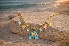 Gold blue mermaid pendant charm necklace with sun and starfish charms on beach by Lumera